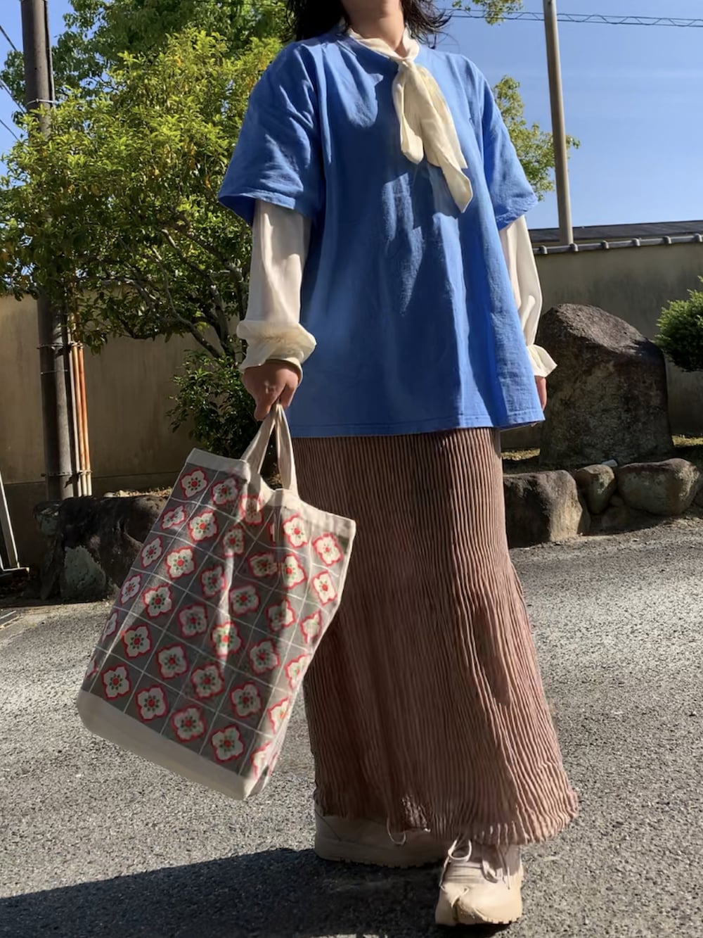 ブラウン系のスカート、ベージュ系のスニーカーを着用したレディースの春コーディネートの2枚目の写真