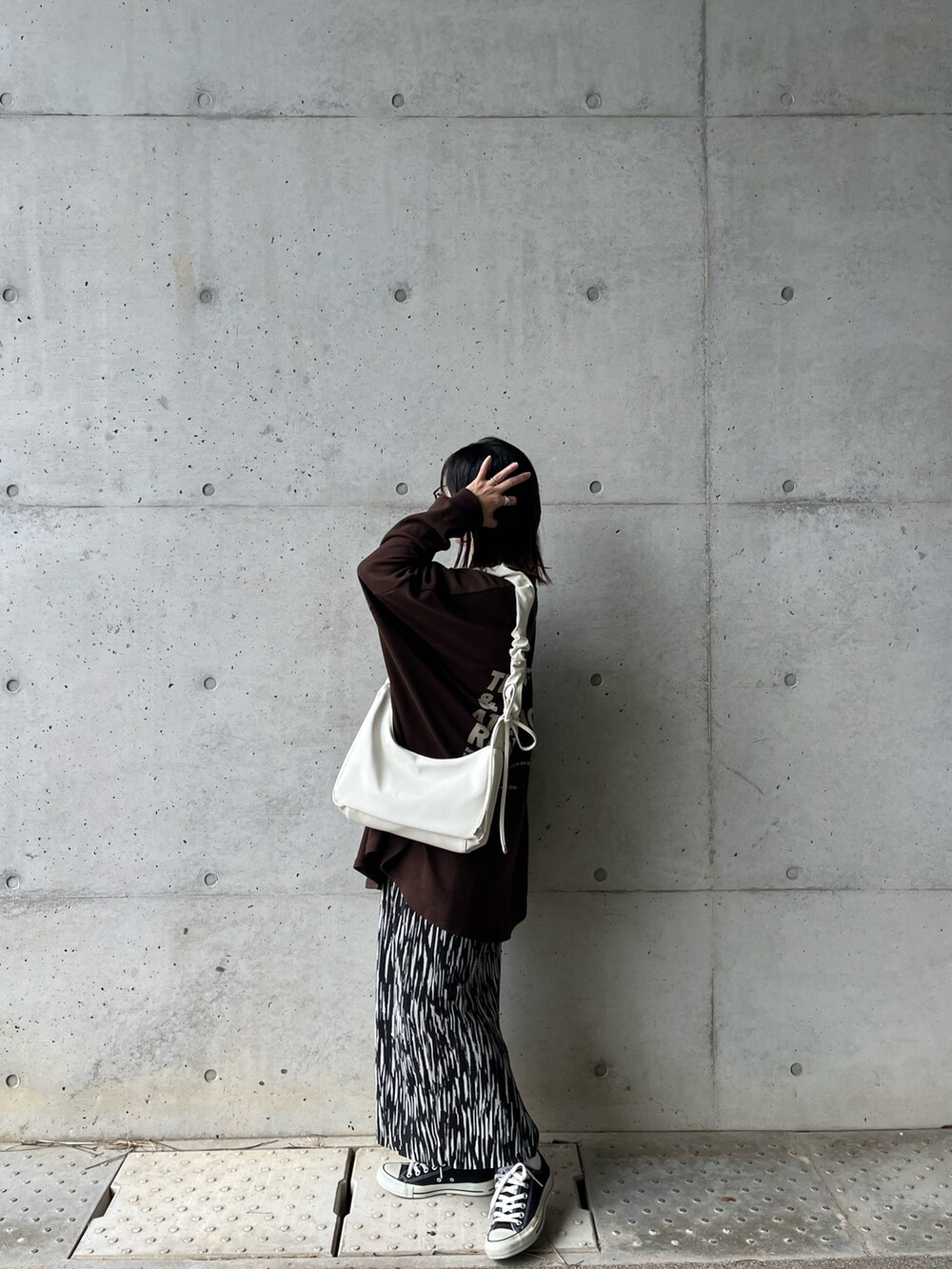 ブラウン系のスウェット、ブラック系のスカート、ホワイト系のショルダーバッグを着用したレディースの冬コーディネートの2枚目の写真