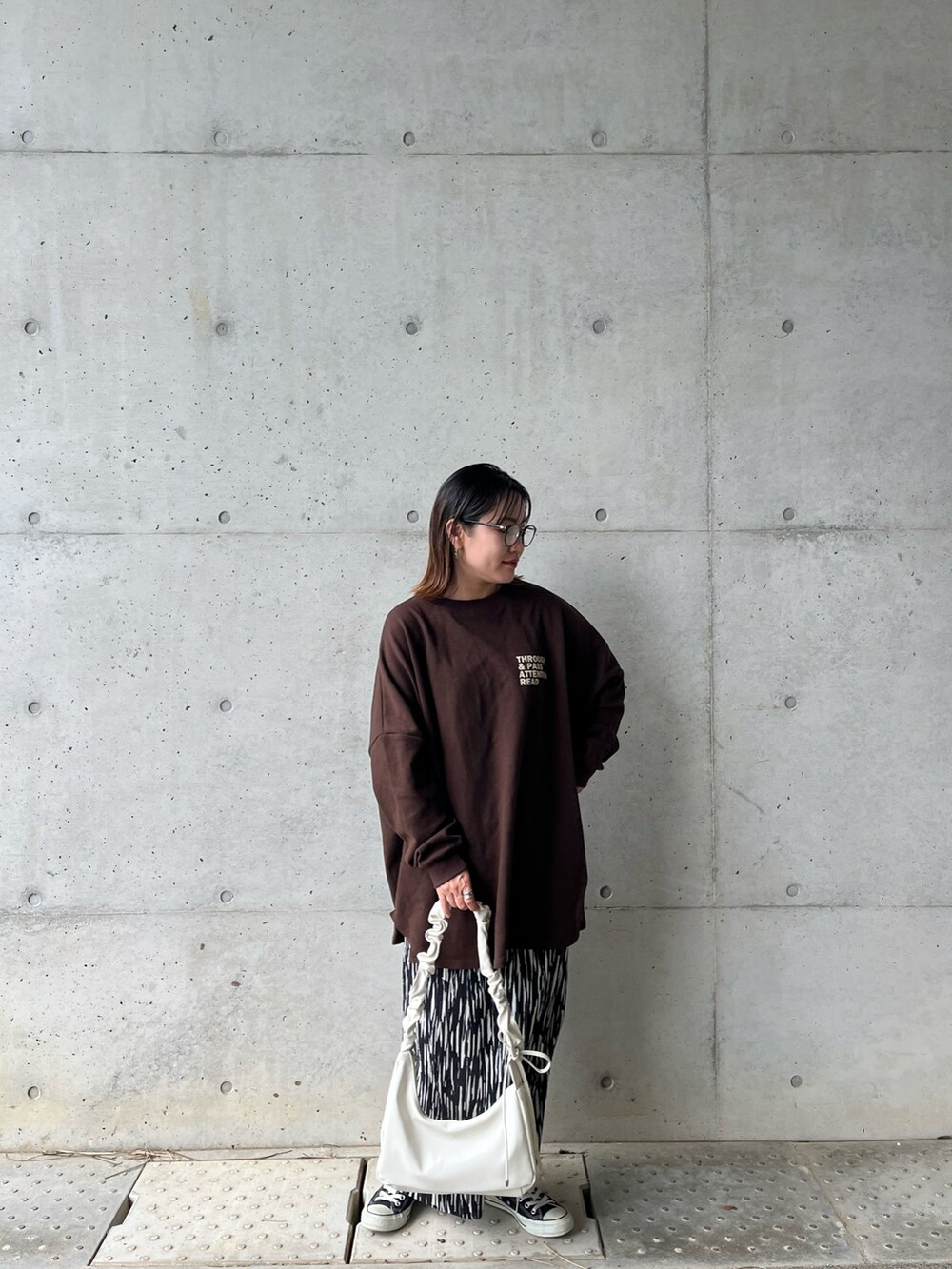 ブラウン系のスウェット、ブラック系のスカート、ホワイト系のショルダーバッグを着用したレディースの冬コーディネートの3枚目の写真