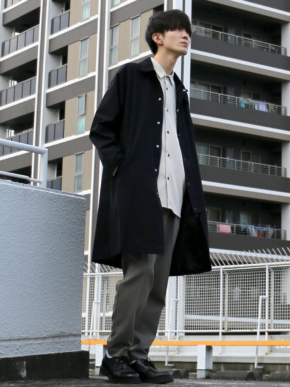 ブラック系のステンカラーコート、ベージュ系のシャツ/ブラウス、グリーン系のスラックスを着用したメンズの秋コーディネートの2枚目の写真