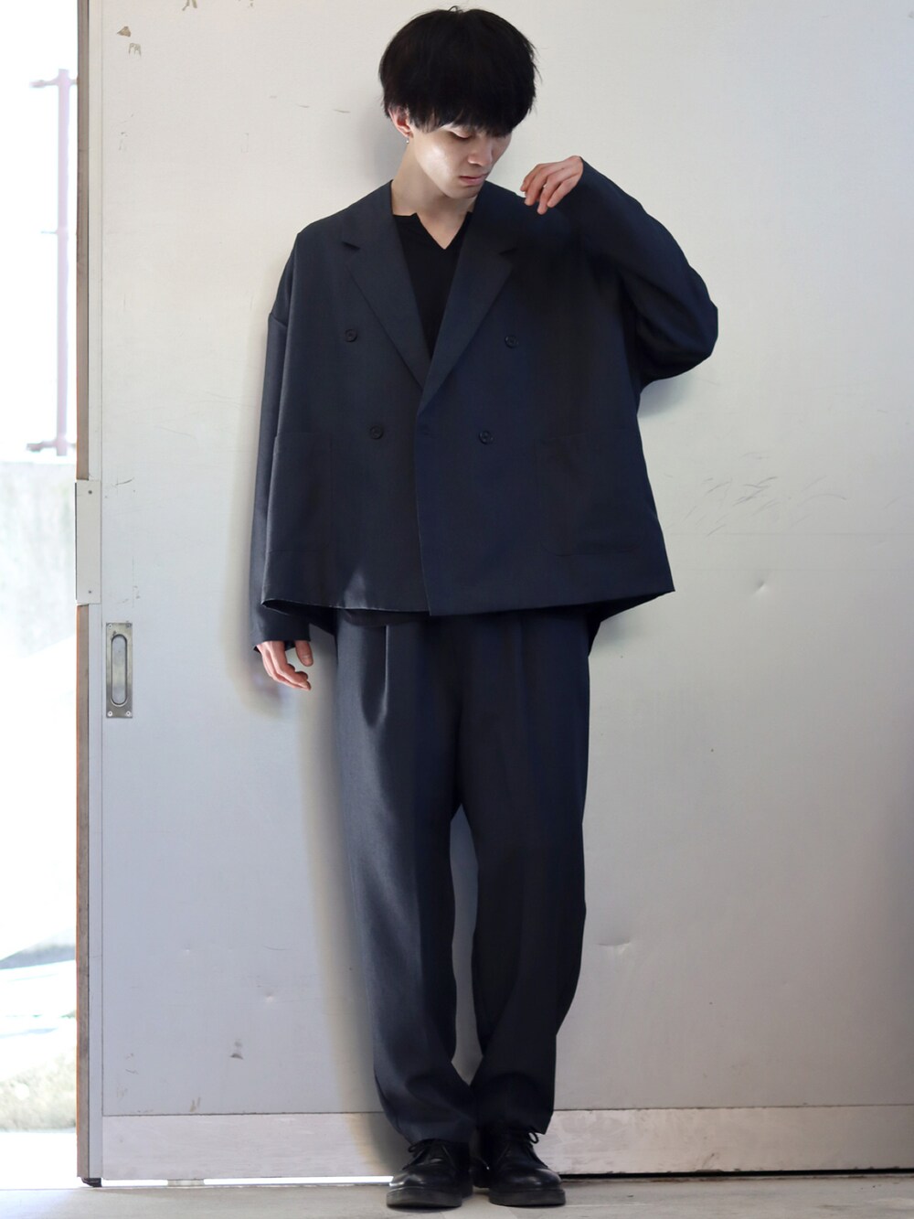 ブラック系のテーラードジャケット、ホワイト系のTシャツ/カットソー、ブラック系のスラックスを着用したメンズの秋コーディネートの3枚目の写真