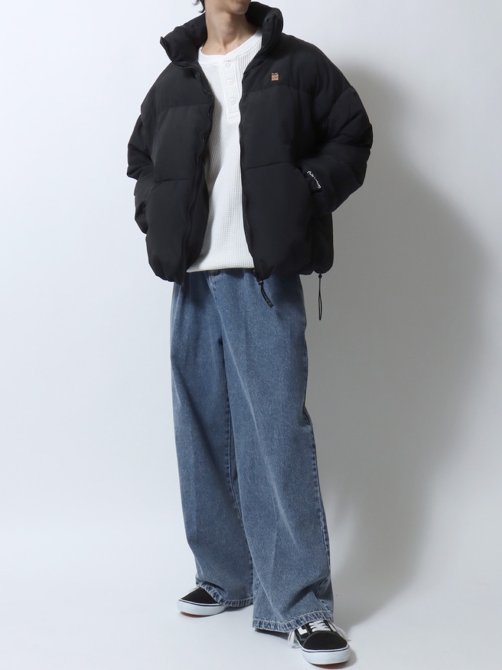 ブラック系のダウンジャケット/コート、ホワイト系のTシャツ/カットソー、ブルー系のデニムパンツを着用したメンズの冬コーディネートの3枚目の写真