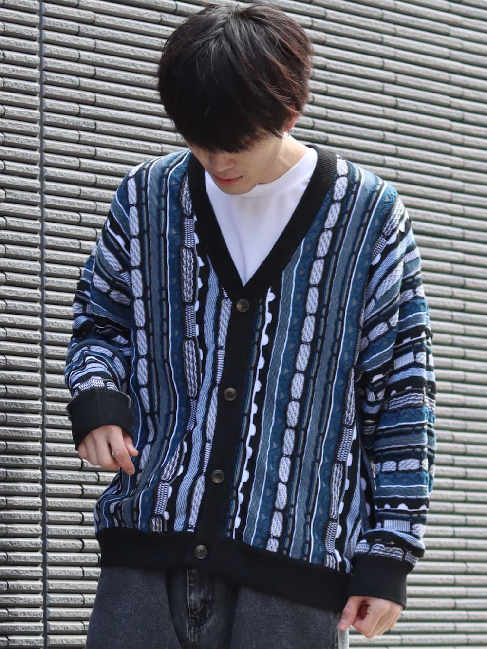 ブラック系のカーディガン/ボレロ、ホワイト系のTシャツ/カットソー、ブラック系のデニムパンツを着用したメンズの冬コーディネートの2枚目の写真