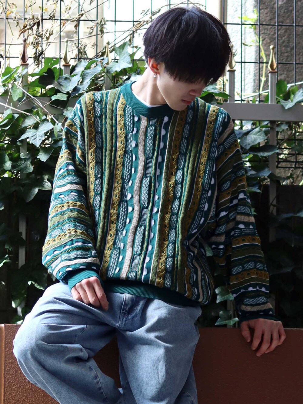 グリーン系のニット/セーター、ブラック系のスニーカー、ブルー系のデニムパンツを着用したメンズの春コーディネートの2枚目の写真