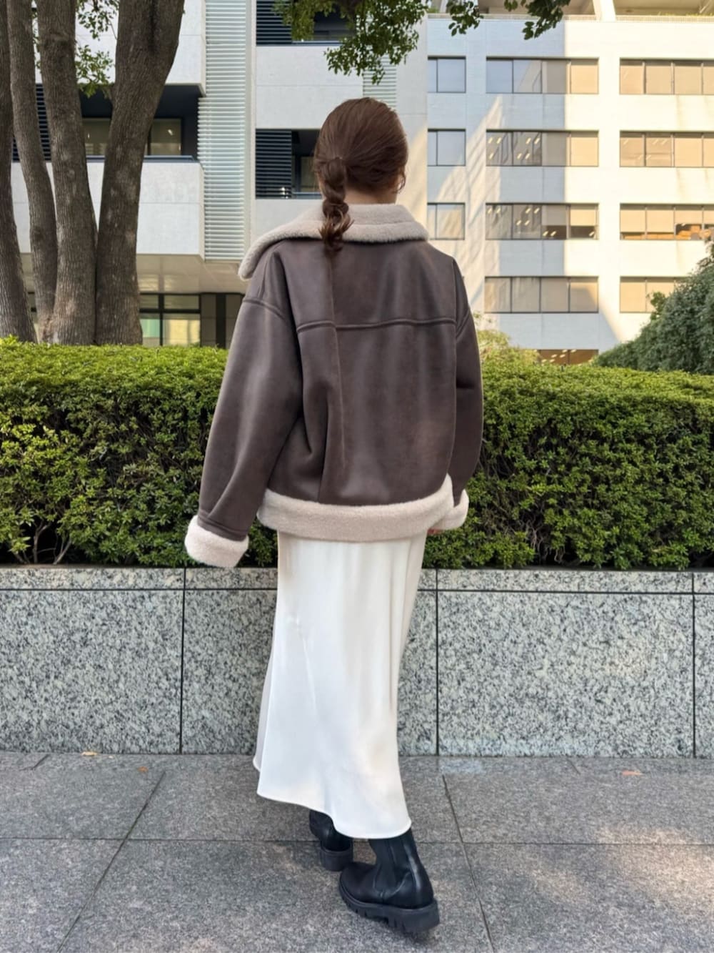 ブラウン系のブルゾン、ホワイト系のスカート、ホワイト系のTシャツ/カットソーを着用したレディースの秋コーディネートの3枚目の写真