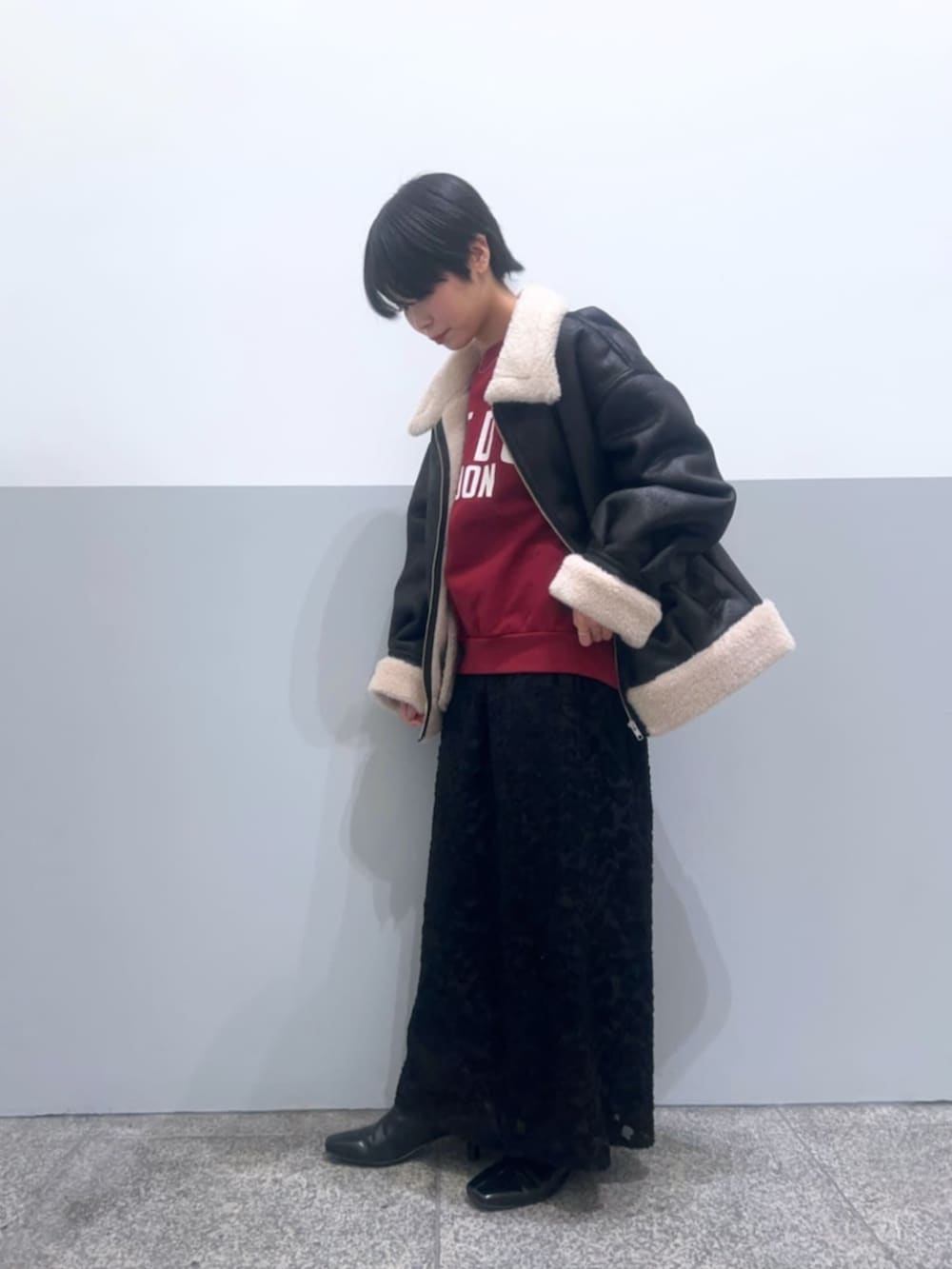 ブラック系のスカート、レッド系のスウェット、ブラック系のブルゾンを着用したレディースの冬コーディネートの2枚目の写真