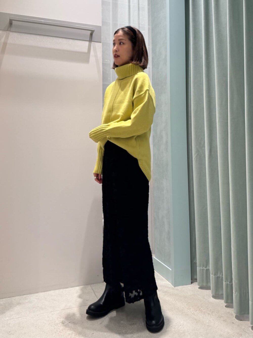 グリーン系のニット/セーター、ブラック系のスカートを着用したレディースの冬コーディネートの2枚目の写真