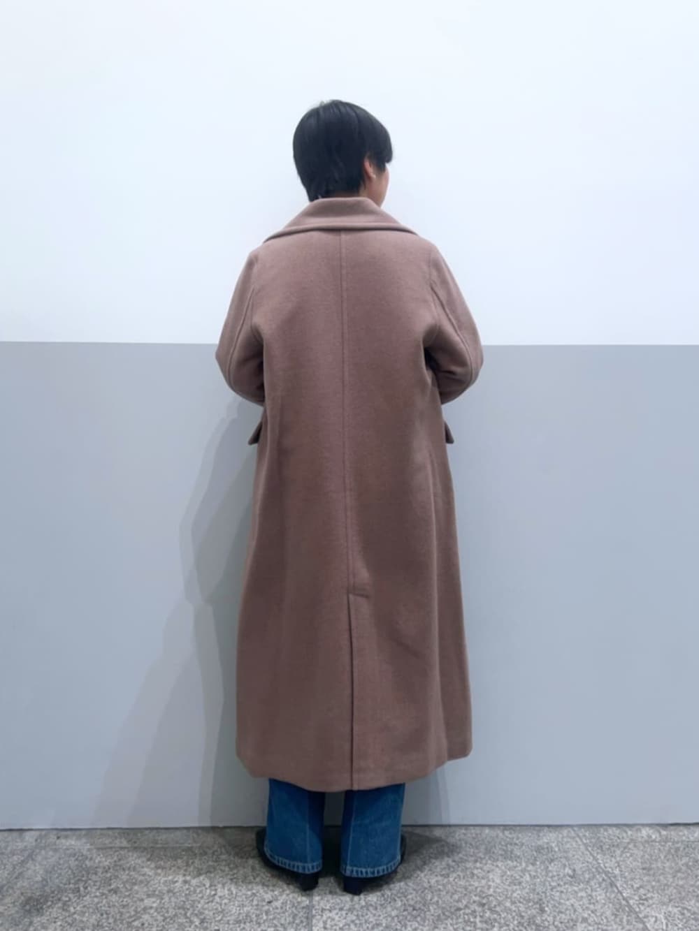 ブラウン系のチェスターコート、ホワイト系のニット/セーター、ブルー系のデニムパンツを着用したレディースの冬コーディネートの3枚目の写真