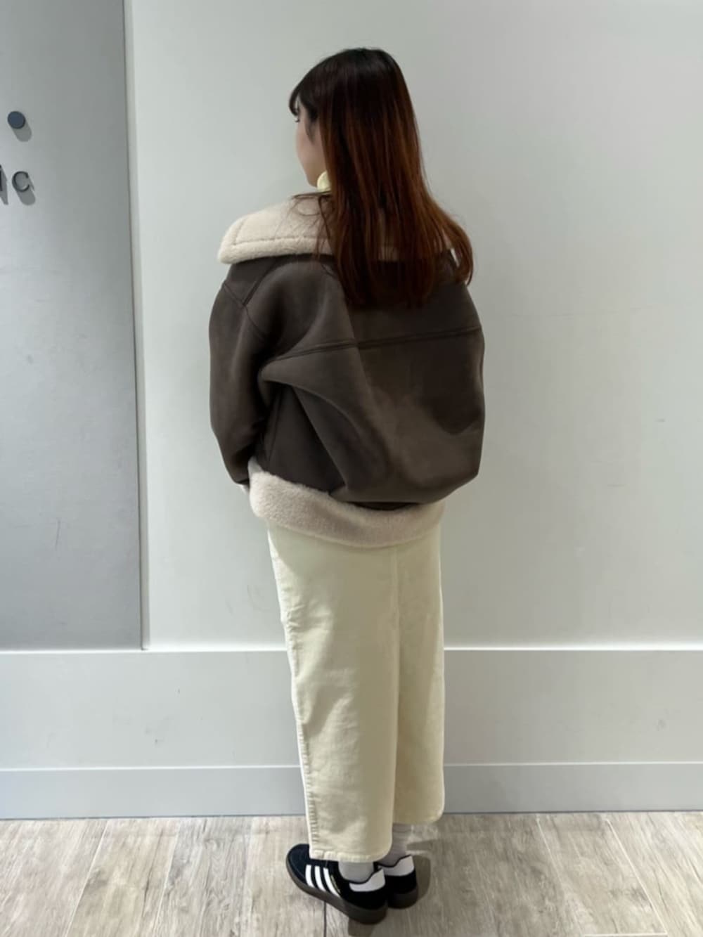 ブラウン系のブルゾン、イエロー系のニット/セーター、ホワイト系のスカートを着用したレディースの冬コーディネートの3枚目の写真