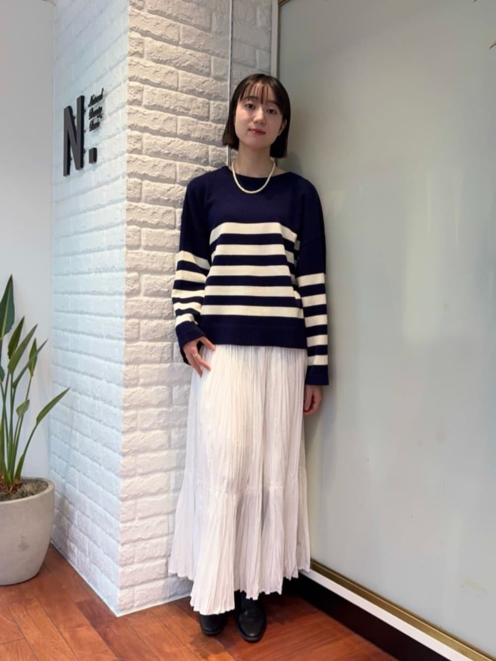 ホワイト系のスカート、ブラウン系のダウンジャケット/コート、ブルー系のニット/セーターを着用したレディースの秋コーディネートの3枚目の写真