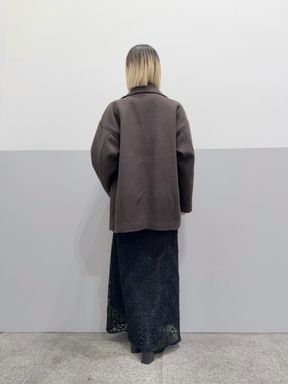 ブラウン系のピーコート、ブラック系のスカートを着用したレディースの冬コーディネートの3枚目の写真