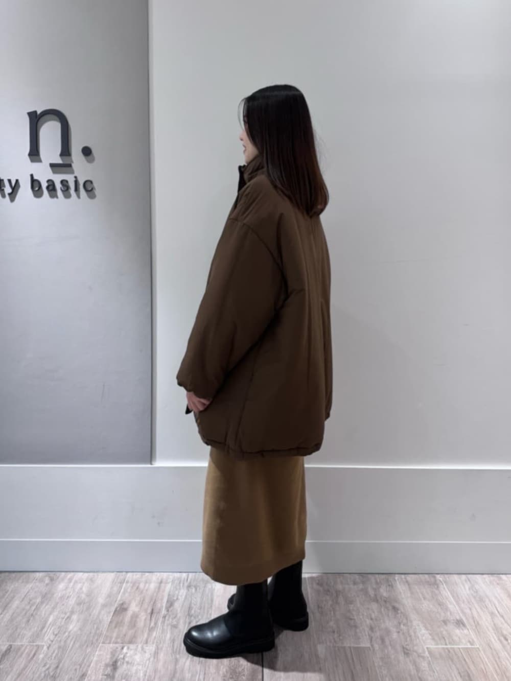 イエロー系のワンピース、ブラウン系のダウンジャケット/コートを着用したレディースの冬コーディネートの2枚目の写真