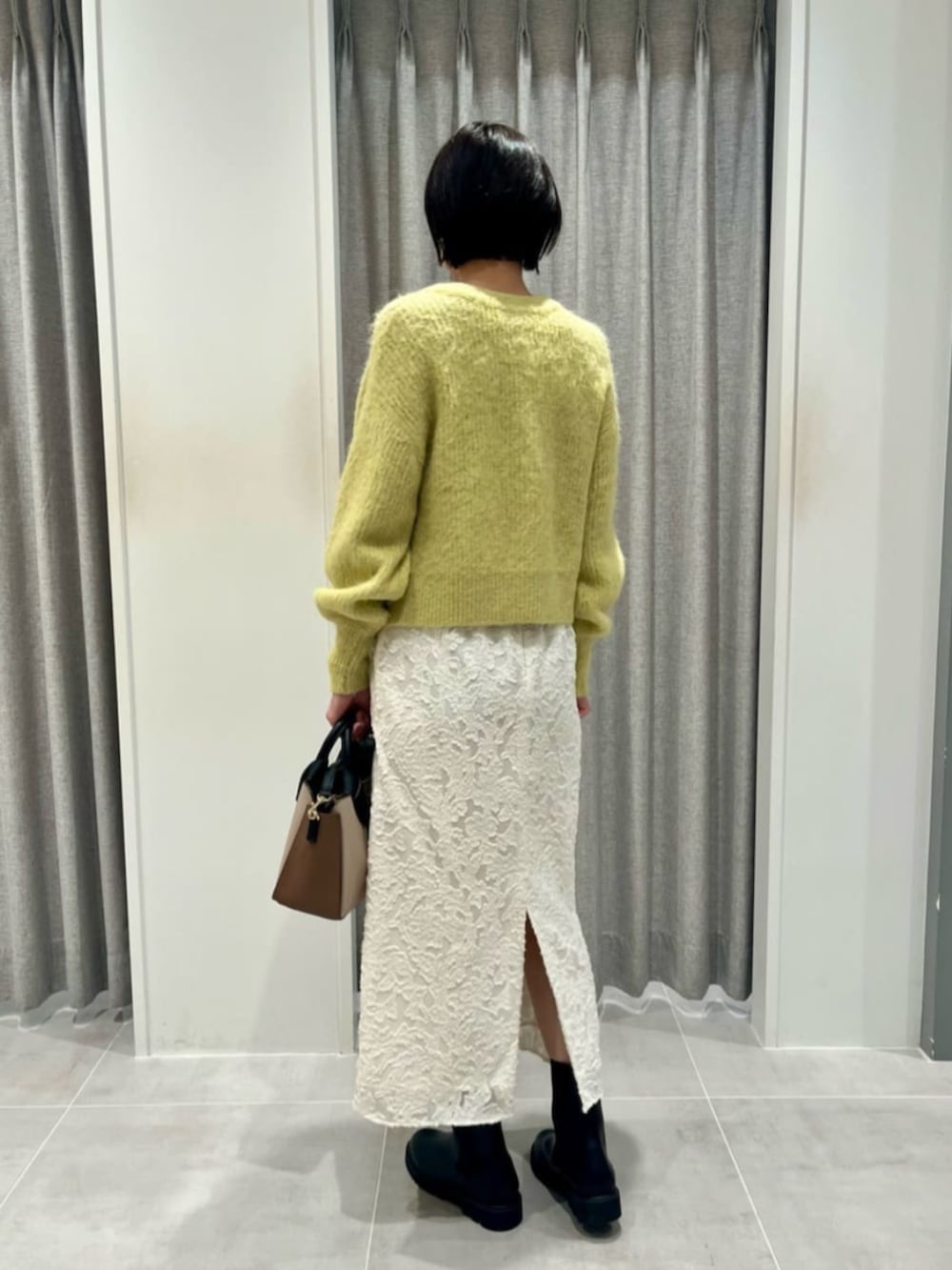 イエロー系のカーディガン/ボレロ、ホワイト系のスカートを着用したレディースの冬コーディネートの3枚目の写真