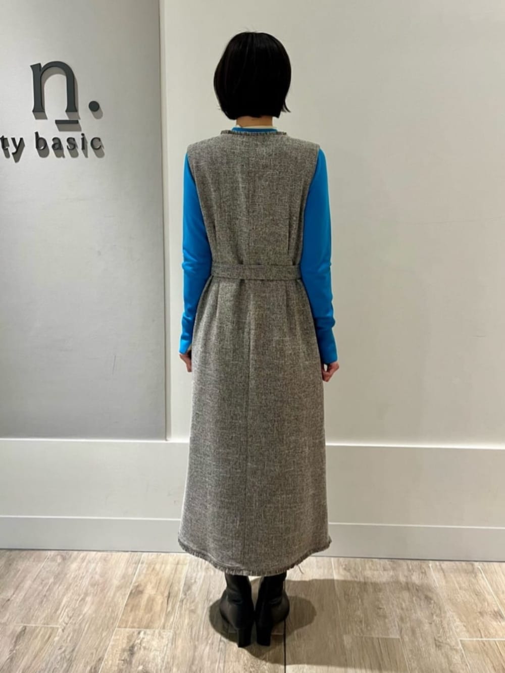 グレー系のジャンパースカート、ブルー系のニット/セーター、ブラック系のチェスターコートを着用したレディースの冬コーディネートの3枚目の写真