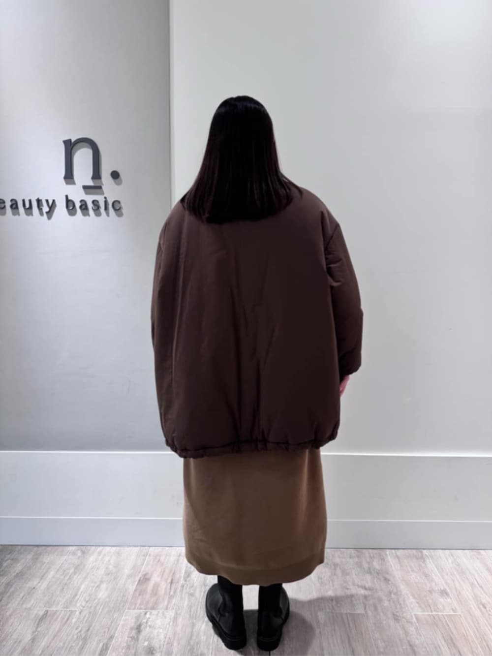 イエロー系のワンピース、ブラウン系のダウンジャケット/コートを着用したレディースの冬コーディネートの3枚目の写真