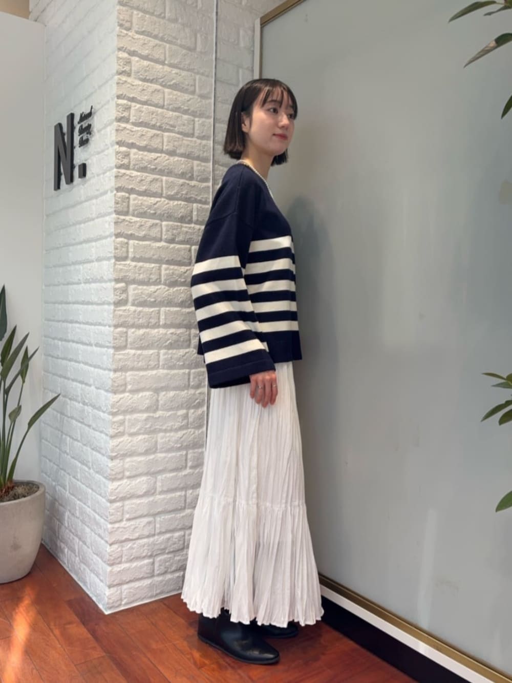 ホワイト系のスカート、ブラウン系のダウンジャケット/コート、ブルー系のニット/セーターを着用したレディースの秋コーディネートの4枚目の写真