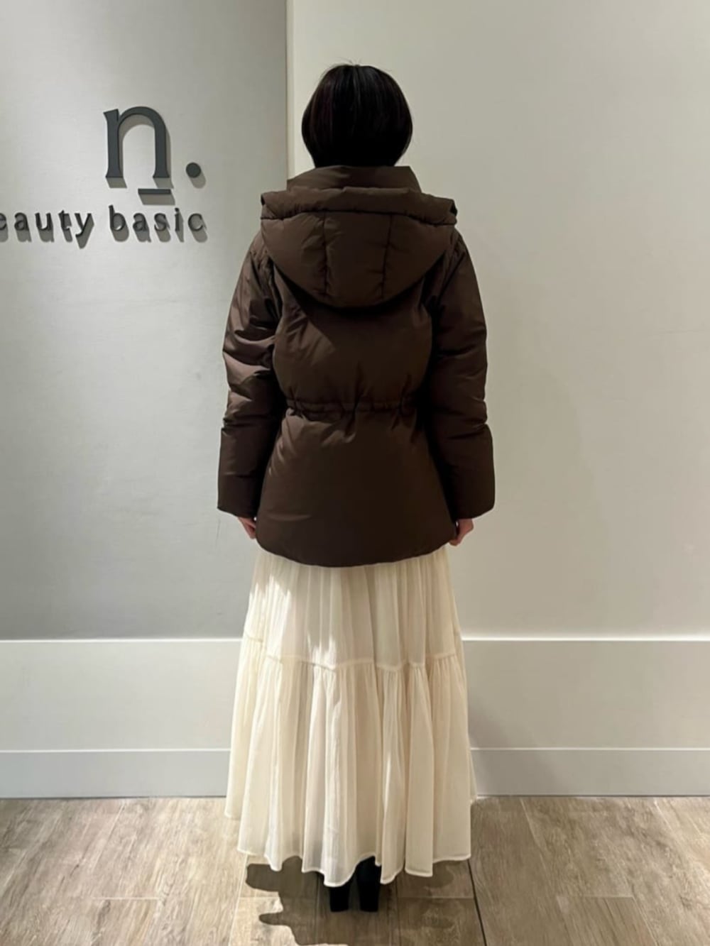 ホワイト系のスカート、グリーン系のニット/セーター、ブラウン系のダウンジャケット/コートを着用したレディースの冬コーディネートの3枚目の写真