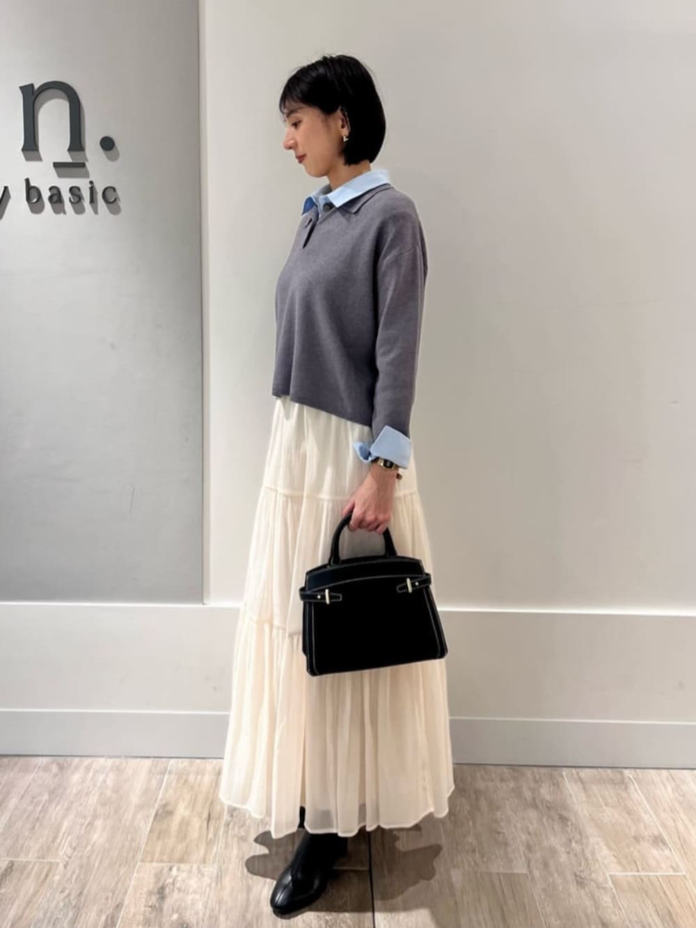 ホワイト系のスカート、グレー系のニット/セーターを着用したレディースの冬コーディネートの2枚目の写真