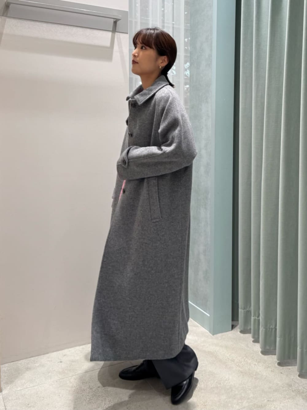 グレー系のステンカラーコート、グレー系のその他パンツ、ピンク系のニット/セーターを着用したレディースの冬コーディネートの2枚目の写真