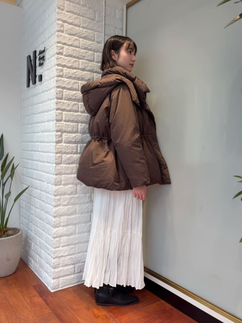 ホワイト系のスカート、ブラウン系のダウンジャケット/コート、ブルー系のニット/セーターを着用したレディースの秋コーディネートの2枚目の写真