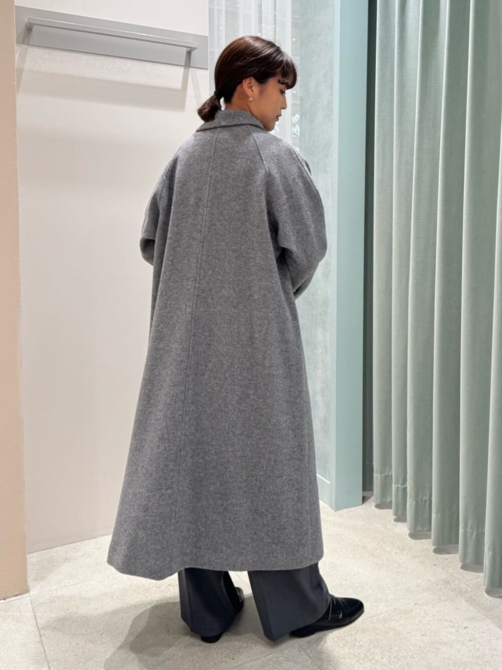 グレー系のステンカラーコート、グレー系のその他パンツ、ピンク系のニット/セーターを着用したレディースの冬コーディネートの3枚目の写真