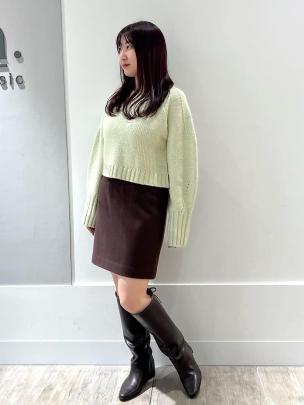 グリーン系のニット/セーター、ブラウン系のスカートを着用したレディースの冬コーディネートの2枚目の写真