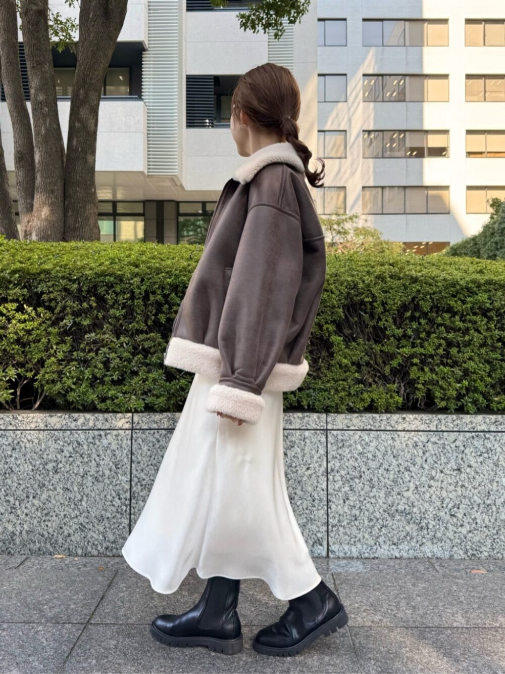 ブラウン系のブルゾン、ホワイト系のスカート、ホワイト系のTシャツ/カットソーを着用したレディースの秋コーディネートの2枚目の写真