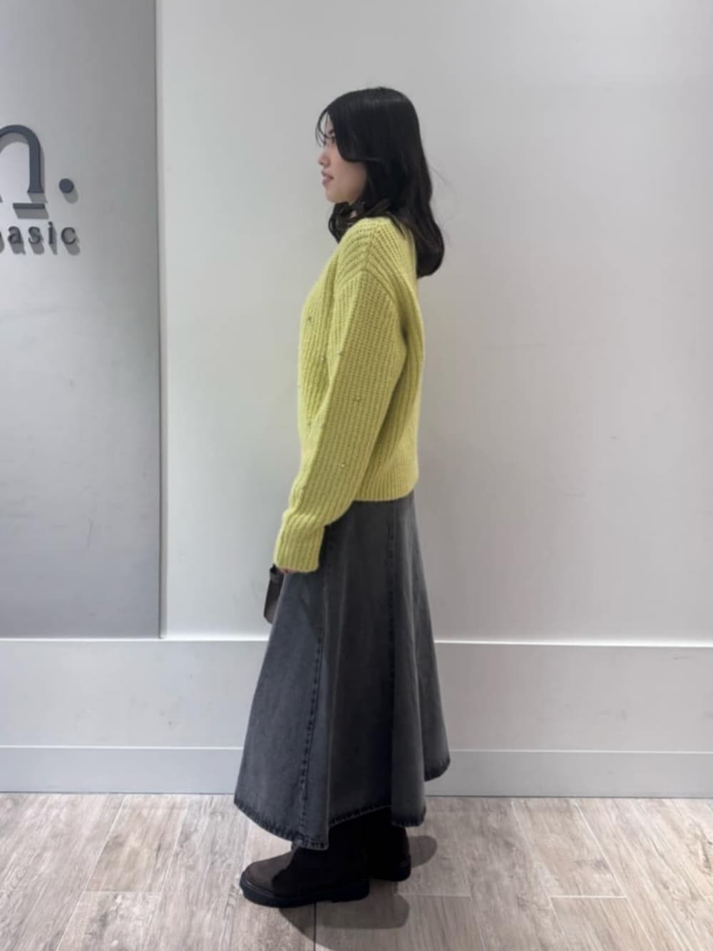 イエロー系のニット/セーター、ブラック系のデニムスカートを着用したレディースの冬コーディネートの2枚目の写真