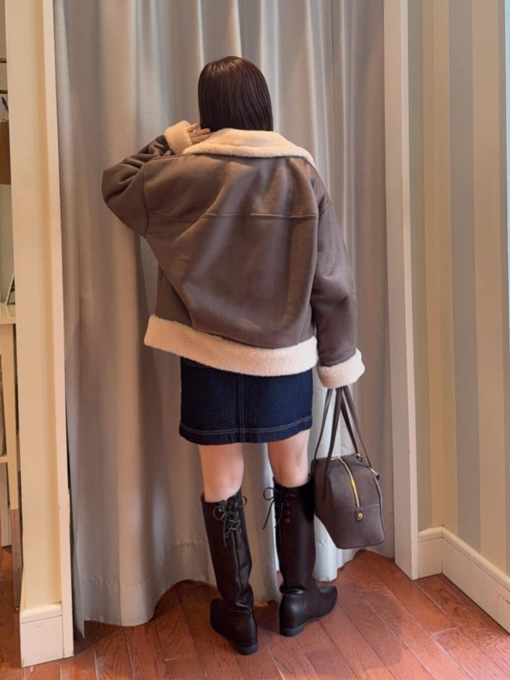 ブラウン系のブルゾン、ブルー系のスカート、イエロー系のニット/セーターを着用したレディースの冬コーディネートの3枚目の写真