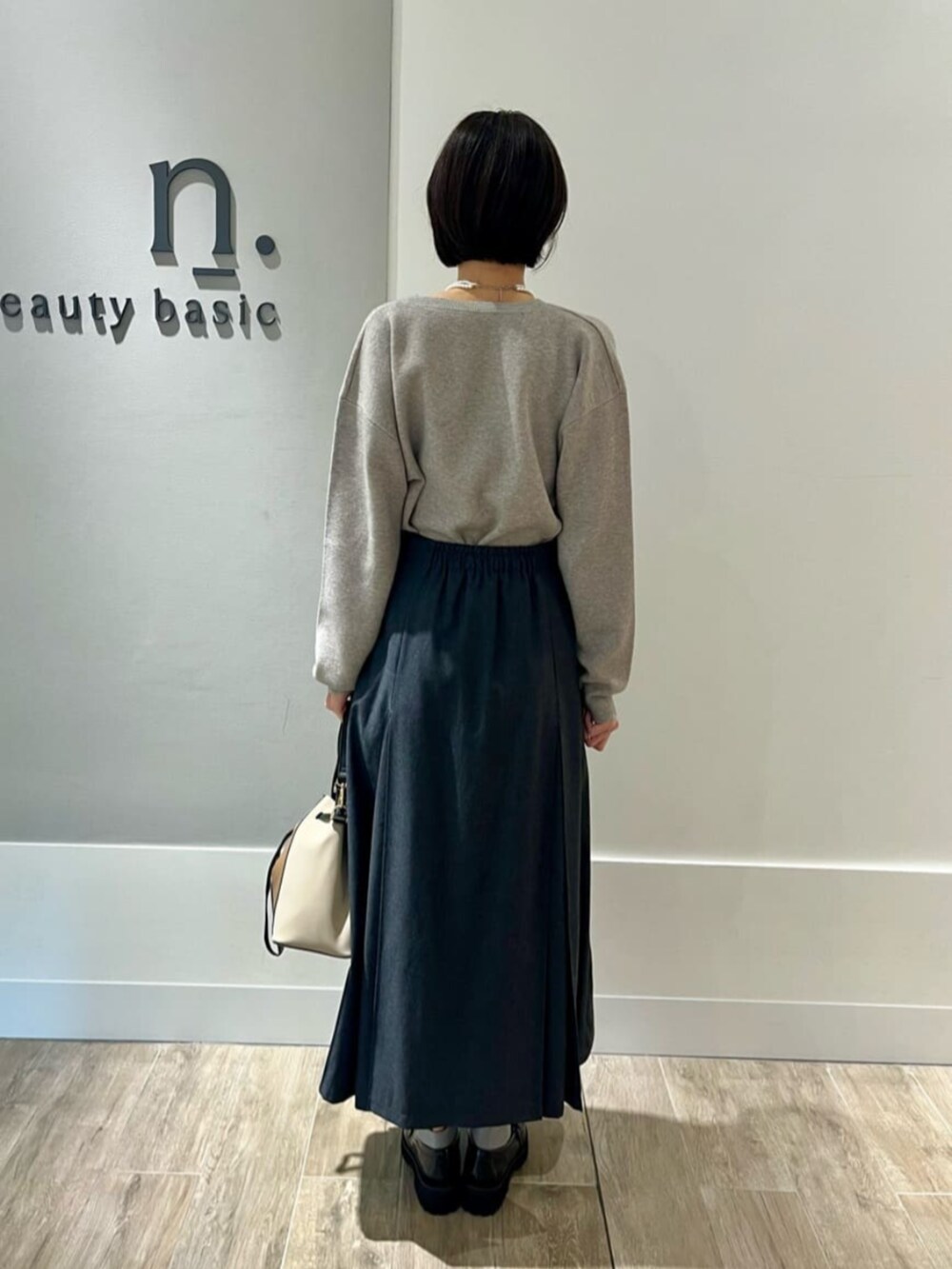 ベージュ系のピーコート、グレー系のニット/セーター、グレー系のスカートを着用したレディースの秋コーディネートの4枚目の写真