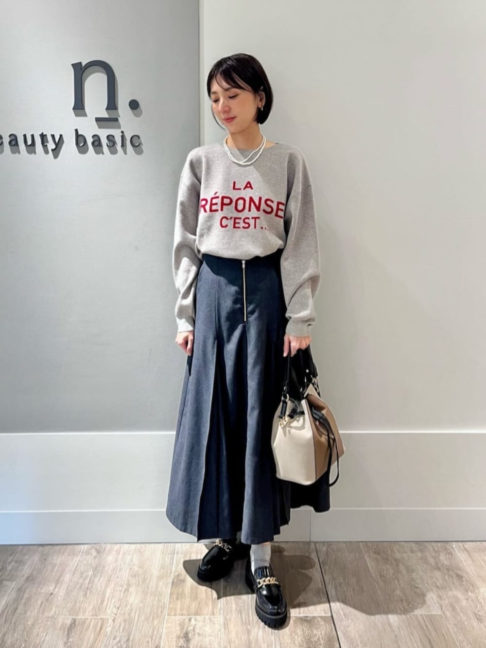 ベージュ系のピーコート、グレー系のニット/セーター、グレー系のスカートを着用したレディースの秋コーディネートの3枚目の写真