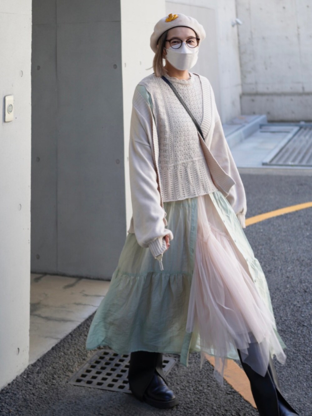 ブラウン系のベスト、ホワイト系のカーディガン/ボレロ、グリーン系のワンピースを着用したレディースの春コーディネートの2枚目の写真