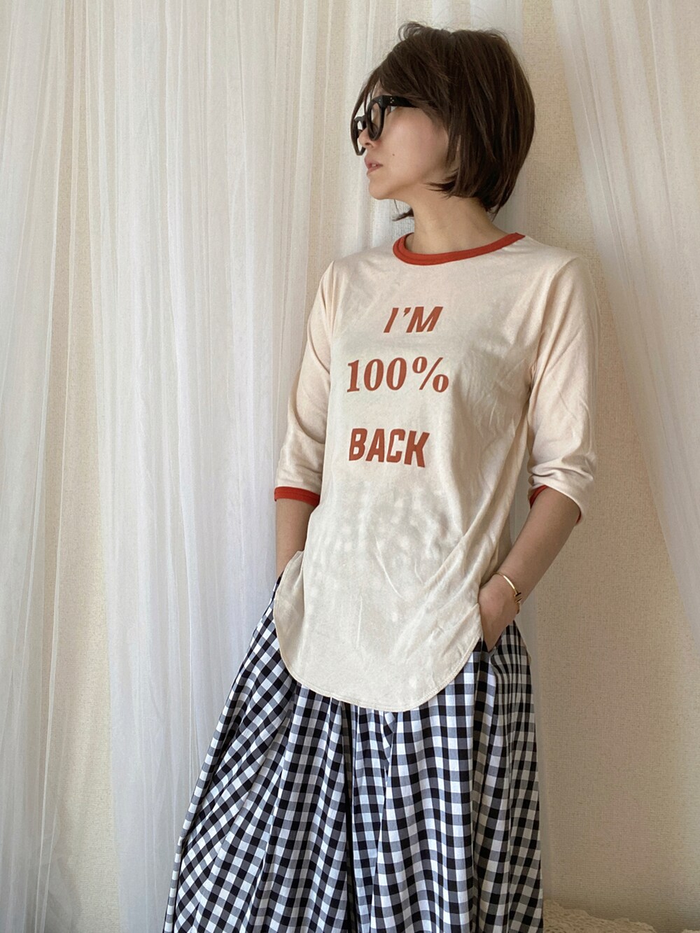 オレンジ系のTシャツ/カットソー、ブラック系のスカート、ブラック系のライダースジャケットを着用したレディースの冬コーディネートの2枚目の写真