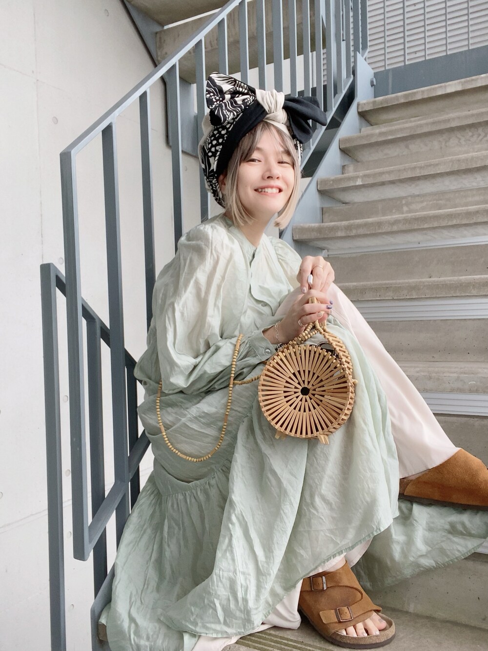 ベージュ系のかごバッグ、グリーン系のワンピース、ホワイト系のワンピースを着用したレディースの春コーディネートの3枚目の写真