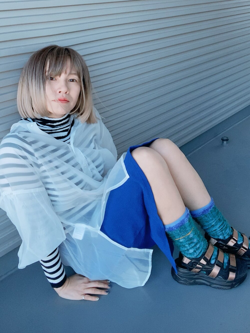 ブラウン系のサンダル、ホワイト系のシャツ/ブラウス、ブルー系のスカートを着用したレディースの春コーディネートの2枚目の写真