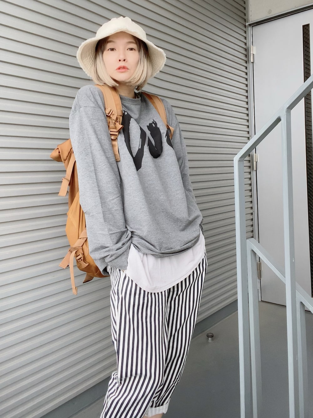 ブラック系のバックパック/リュック、ブルー系のパンツ、ブラウン系のサンダルを着用したレディースの春コーディネートの2枚目の写真