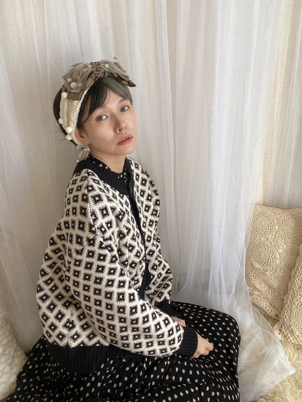 ブラック系のワンピース、ホワイト系のカーディガン/ボレロ、シルバー系のシューズを着用したレディースの春コーディネートの2枚目の写真