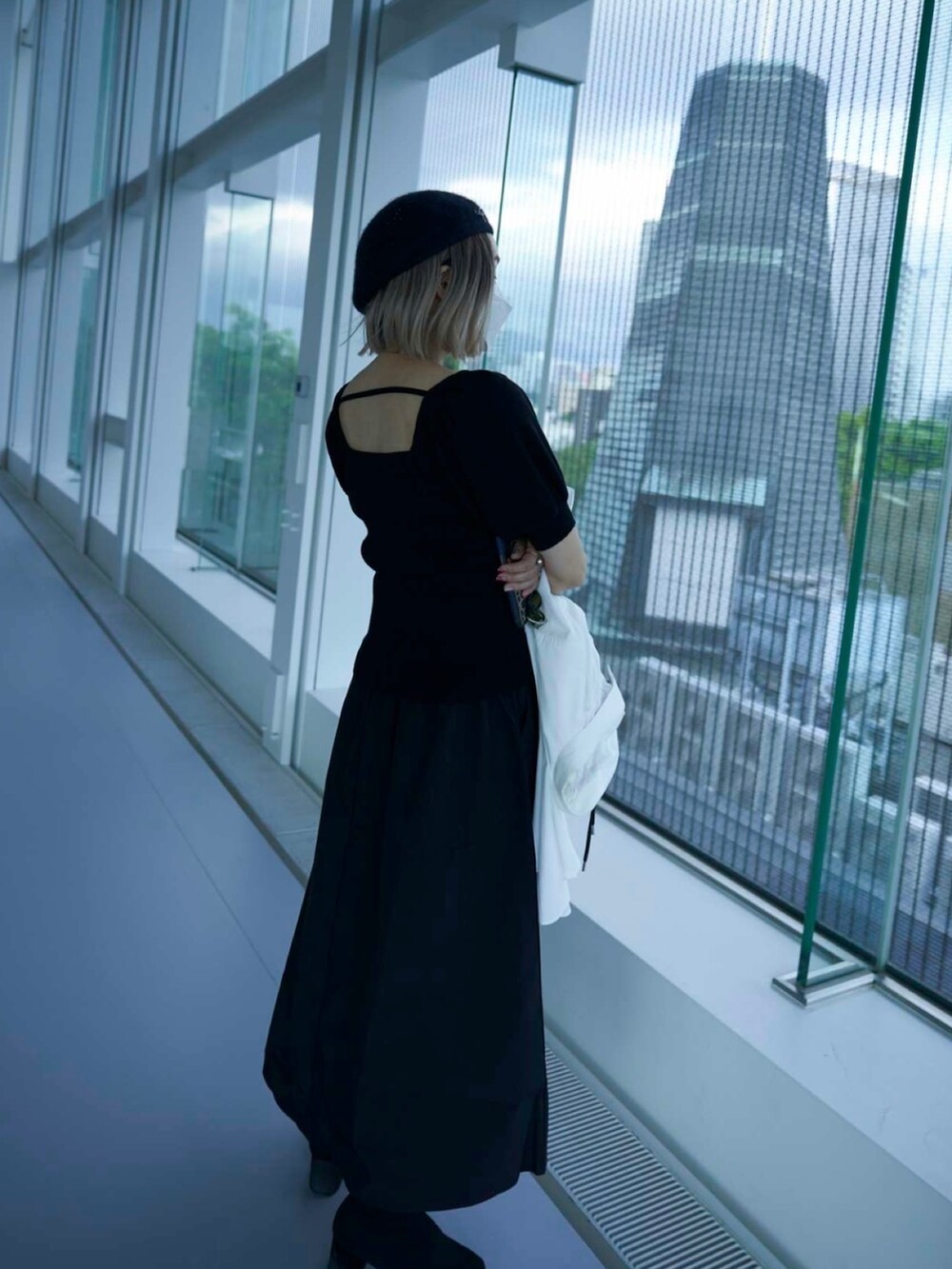 グリーン系のバッグ、ホワイト系のワンピース、ブラック系のブーツを着用したレディースの春コーディネートの3枚目の写真