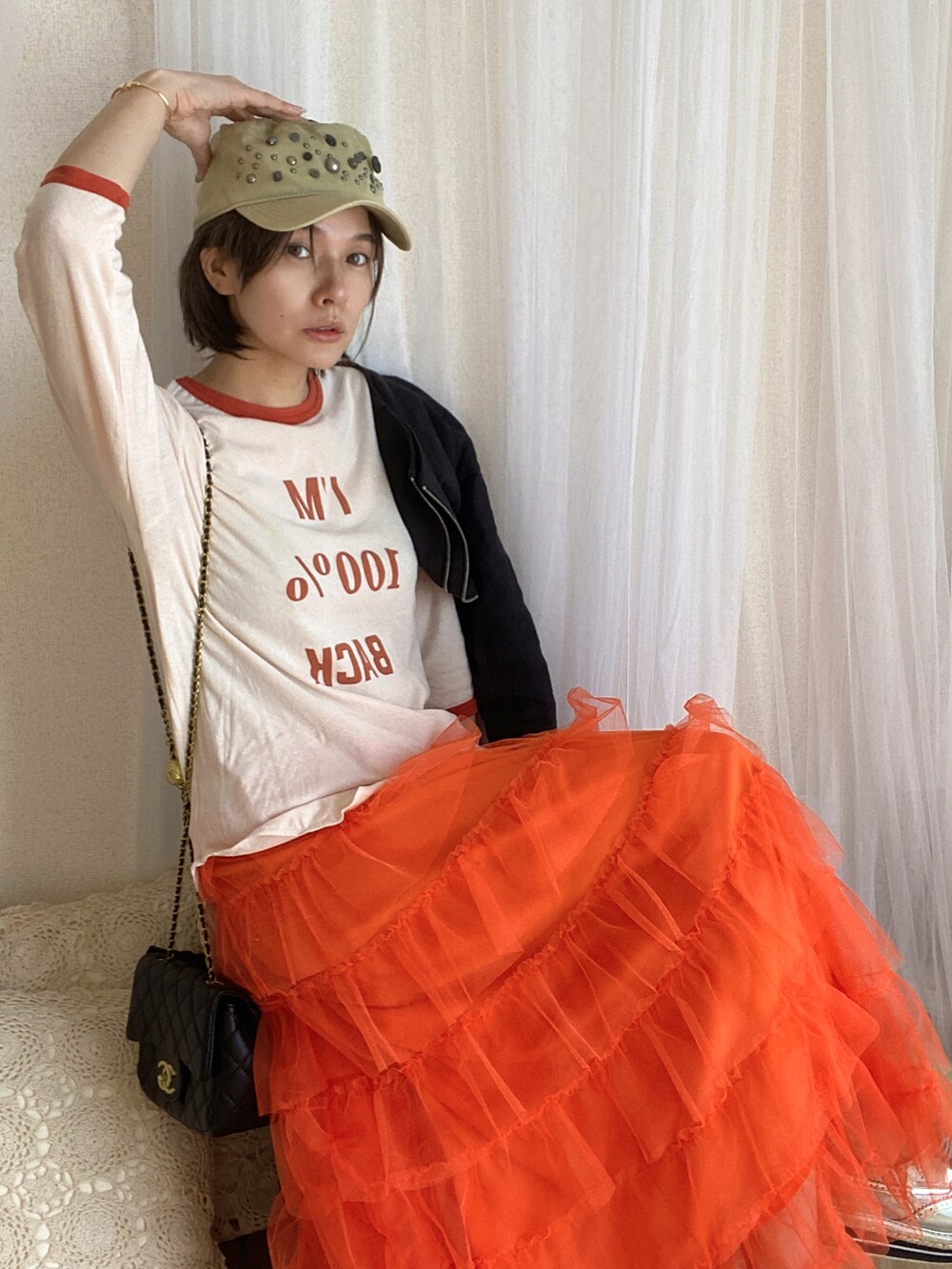 オレンジ系のTシャツ/カットソー、オレンジ系のスカート、シルバー系のシューズを着用したレディースの冬コーディネートの3枚目の写真