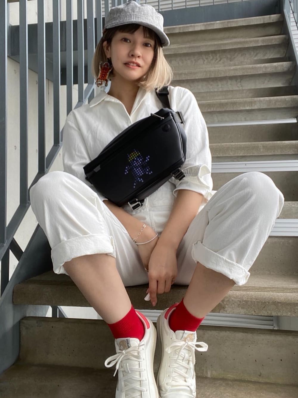 ホワイト系のスニーカー、ホワイト系のオールインワン・サロペット、グレー系のキャップを着用したレディースの春コーディネートの2枚目の写真