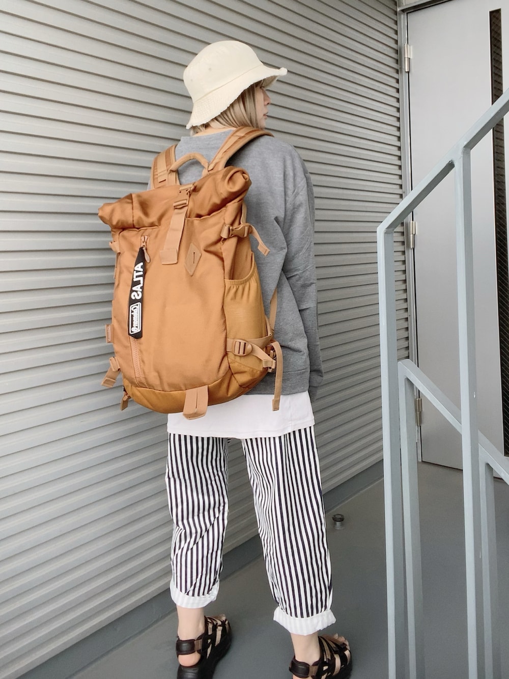 ブラック系のバックパック/リュック、ブルー系のパンツ、ブラウン系のサンダルを着用したレディースの春コーディネートの3枚目の写真