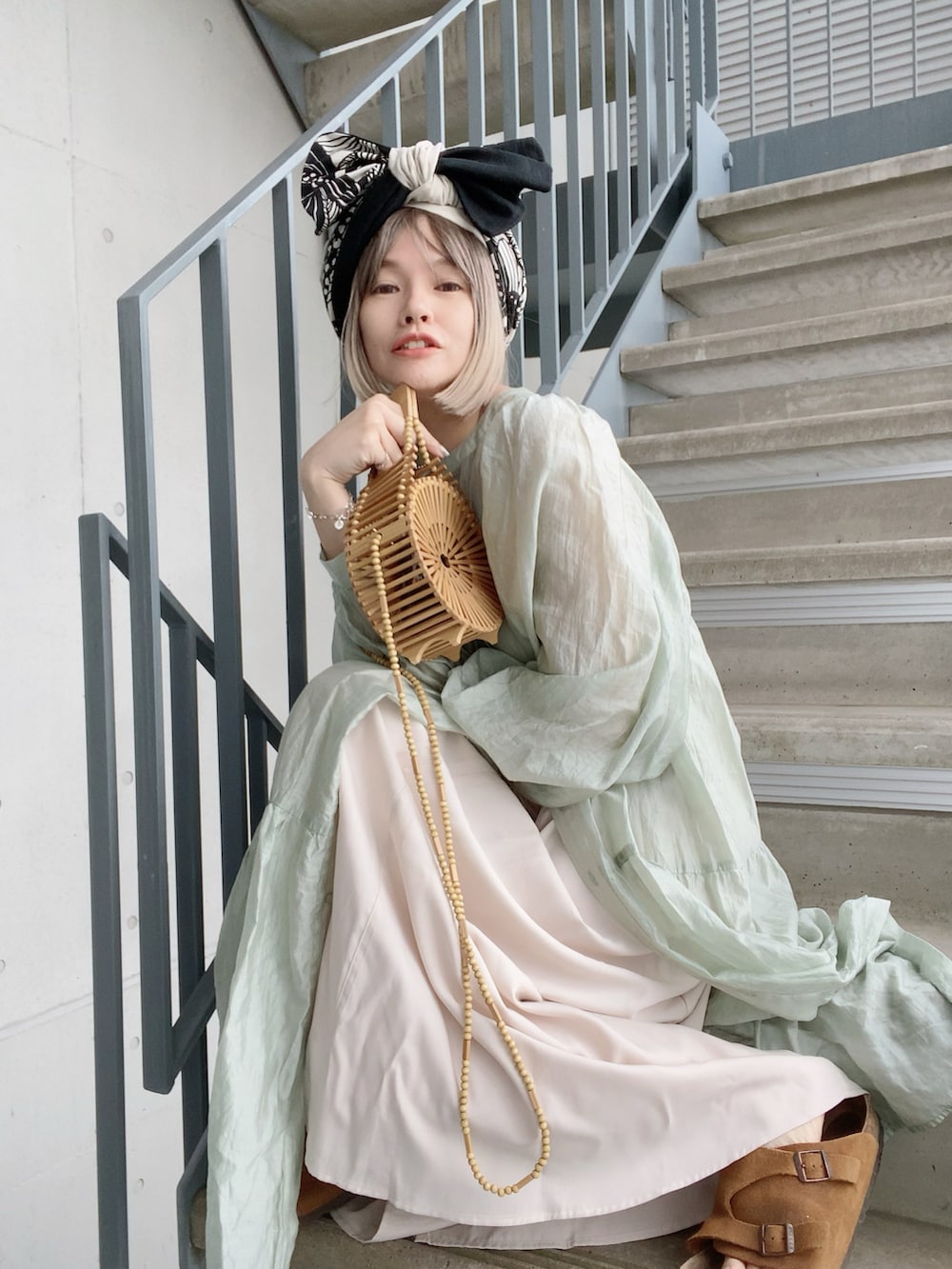 ベージュ系のかごバッグ、グリーン系のワンピース、ホワイト系のワンピースを着用したレディースの春コーディネートの2枚目の写真