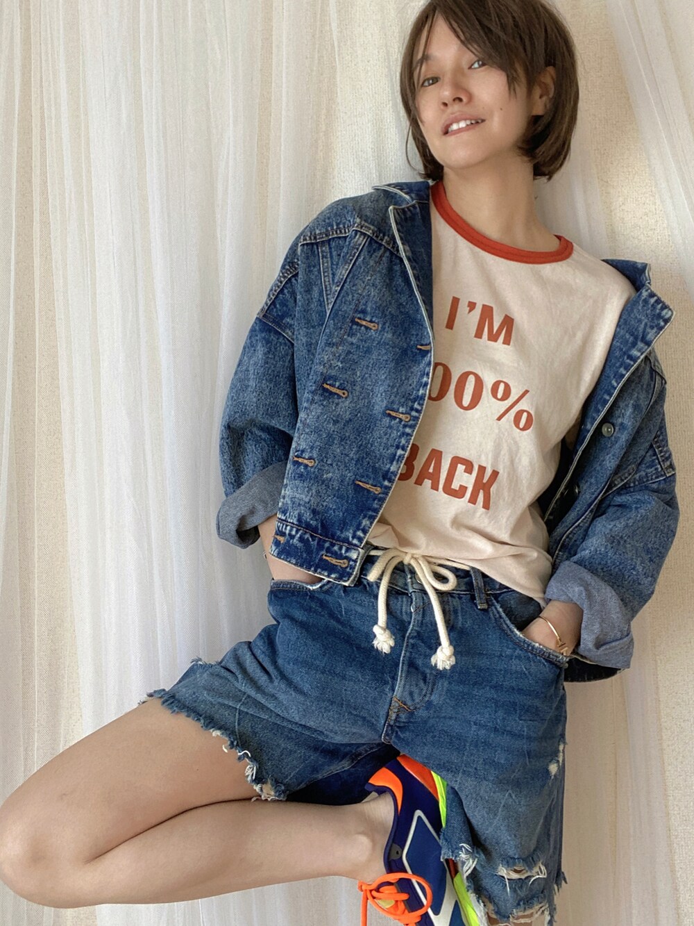 ブルー系のデニムパンツ、ブルー系のデニムジャケット、オレンジ系のTシャツ/カットソーを着用したレディースの冬コーディネートの3枚目の写真