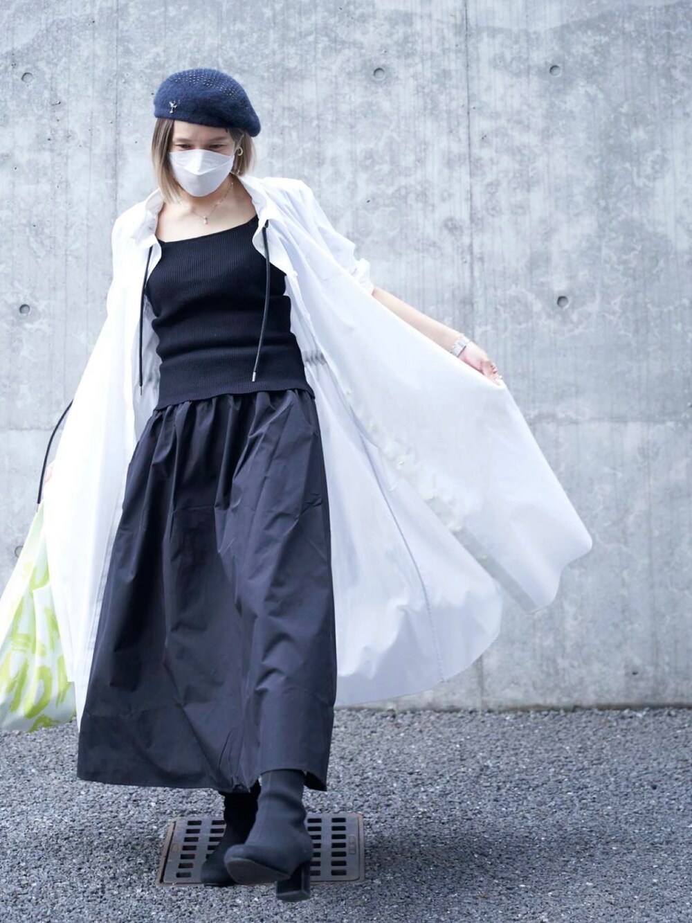 グリーン系のバッグ、ホワイト系のワンピース、ブラック系のブーツを着用したレディースの春コーディネートの2枚目の写真