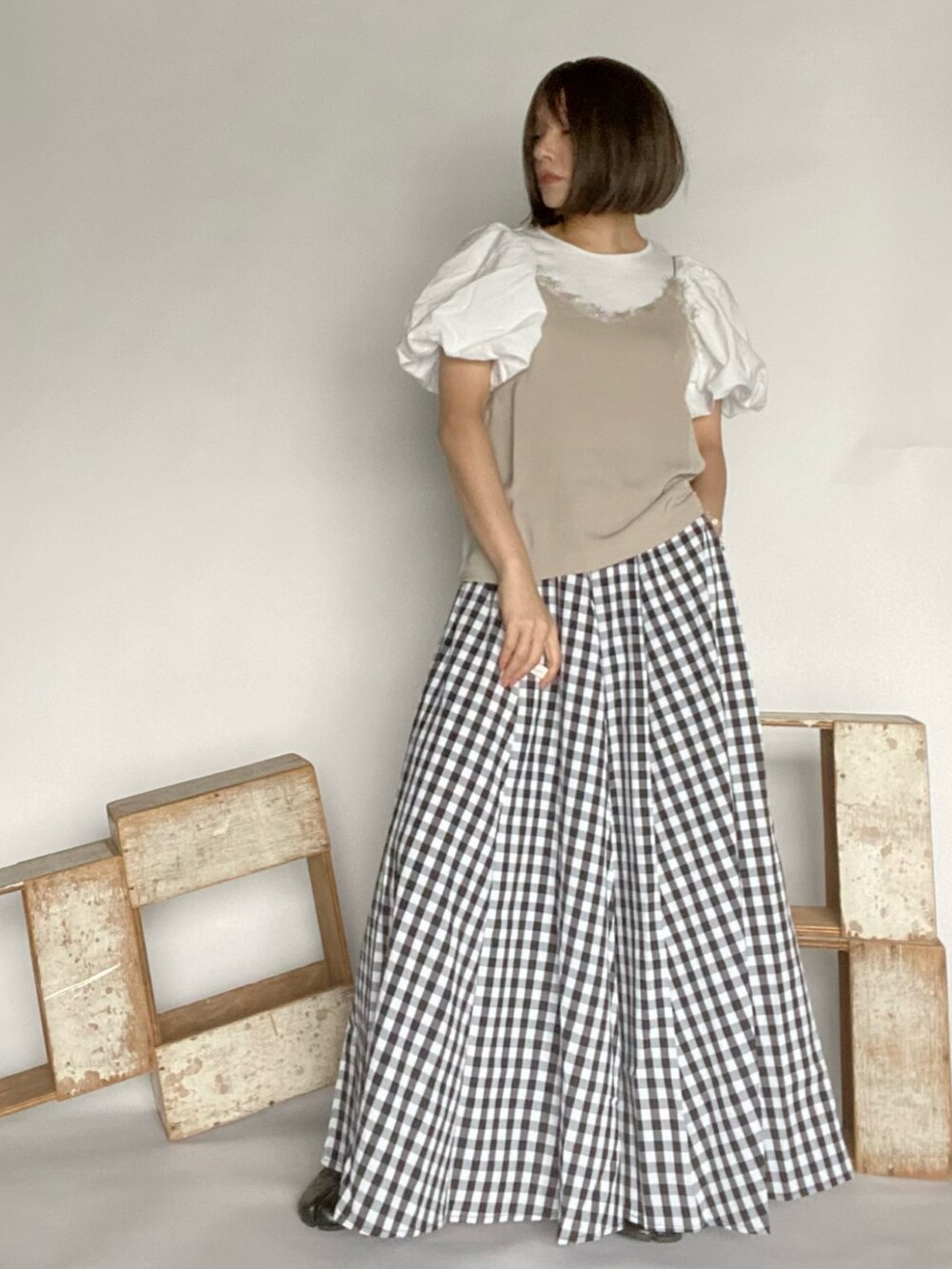 ベージュ系のキャミソール、ブラック系のスカート、ブラック系のシューズを着用したレディースの春コーディネートの3枚目の写真