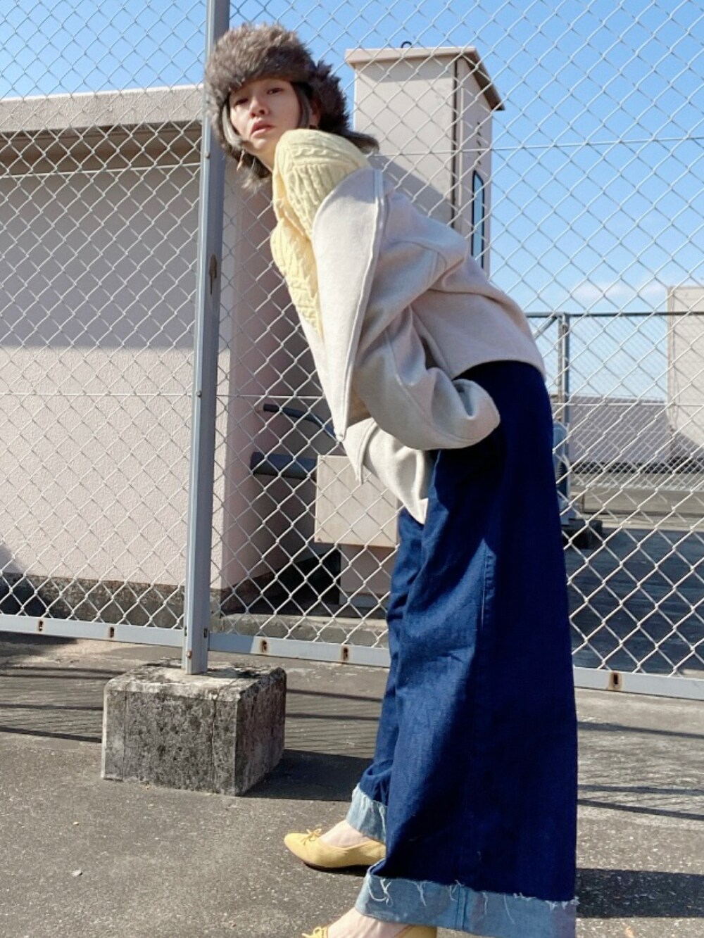 ブルー系のデニムパンツ、イエロー系のシューズ、グレー系のキャップを着用したレディースの冬コーディネートの2枚目の写真
