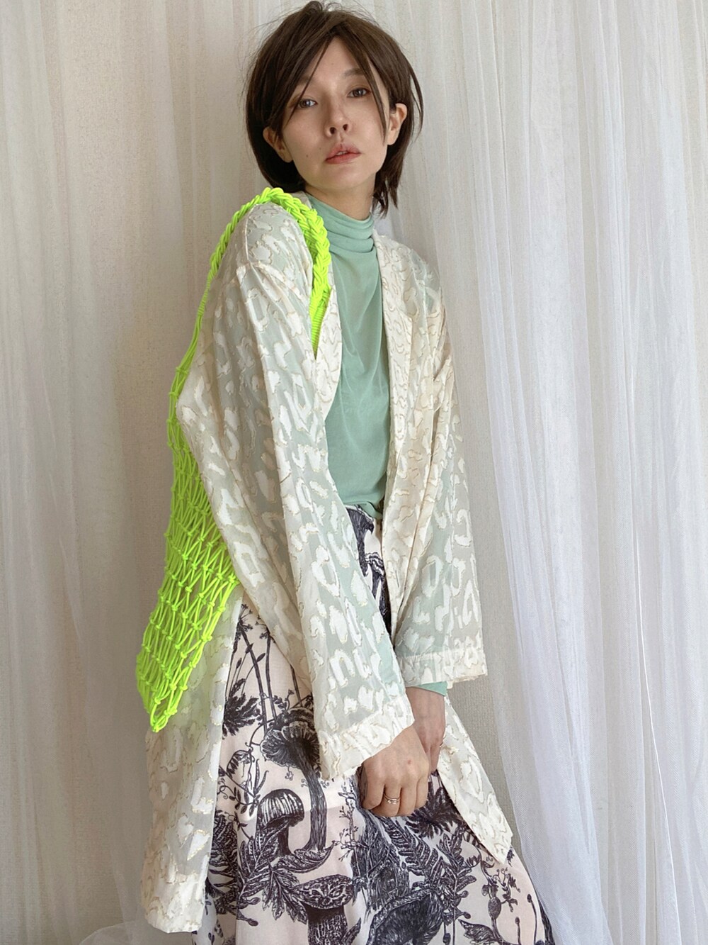 グリーン系のTシャツ/カットソー、ホワイト系のスカート、ホワイト系のテーラードジャケットを着用したレディースの冬コーディネートの4枚目の写真