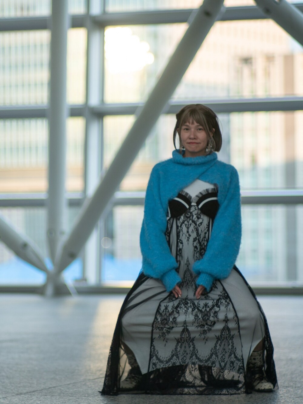 シルバー系のバッグ、ブラック系のステンカラーコート、ブラック系のワンピースを着用したレディースの冬コーディネートの2枚目の写真