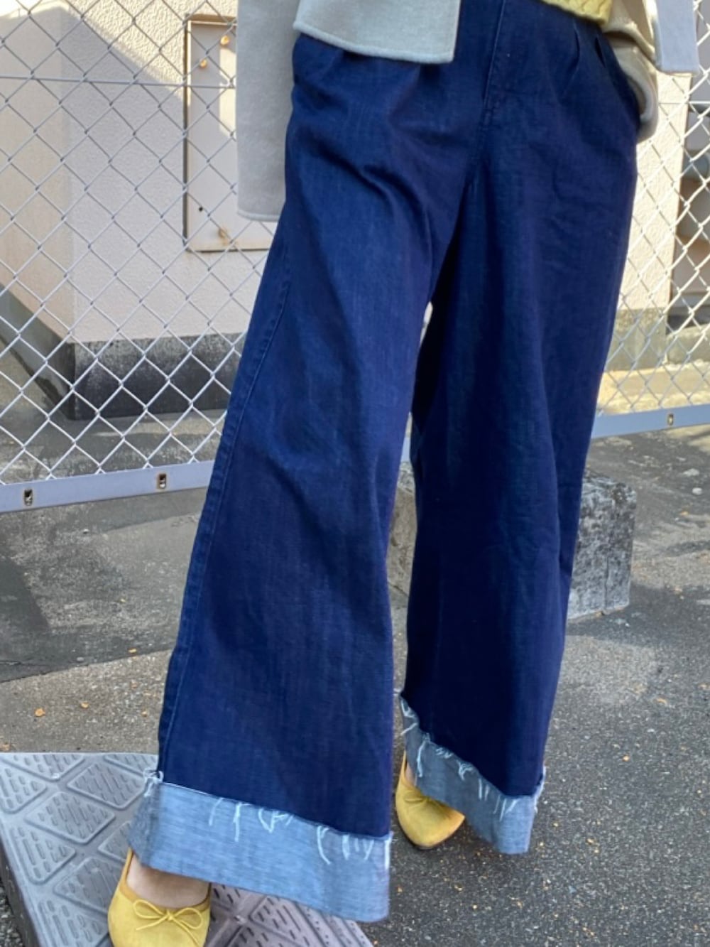 ブルー系のデニムパンツ、イエロー系のシューズ、グレー系のキャップを着用したレディースの冬コーディネートの4枚目の写真