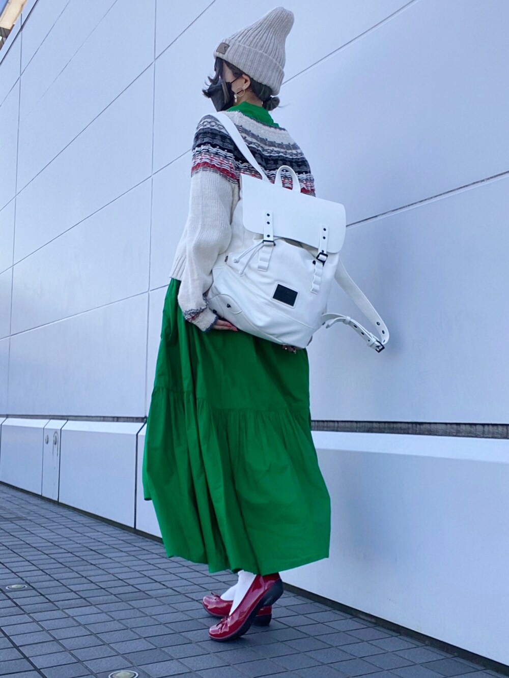 レッド系のパンプス、グリーン系のワンピース/ドレス、ホワイト系のバックパック/リュックを着用したレディースの秋コーディネートの2枚目の写真